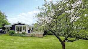 Ein modernes Haus mit großem Panoramafenster, einem gepflegten Rasen und einem Baum.