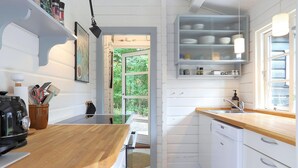 Eine kleine Küche mit weißen Schränken, einer Holz Arbeitsplatte und einem Fenster, das für natürliches Licht sorgt.