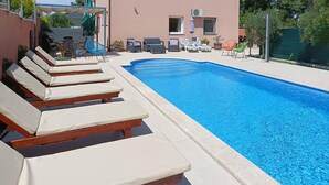 En pool med solstolar och ett avskärmat område med sittplatser.