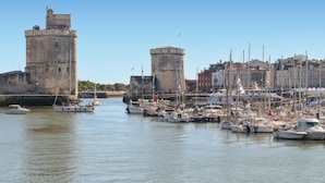 A historic waterfront with a prominent tower and a marina filled with boats. - Awesome home in Rochefort (Rochefort)