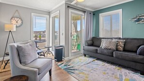 A living room with a gray sofa, a gray armchair, a floor lamp, and a patterned rug. - Oceanfront Resort 2Br Condo Pools and Hot Tubs (Myrtle Beach)
