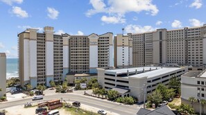 A multi-story hotel with a parking garage, located near a beach. - Penthouse End Unit with Panoramic Oceanfront View (North Myrtle Beach)