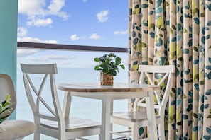A balcony with a view of the sea, featuring a round table with chairs and a potted plant. - Penthouse End Unit with Panoramic Oceanfront View (North Myrtle Beach)