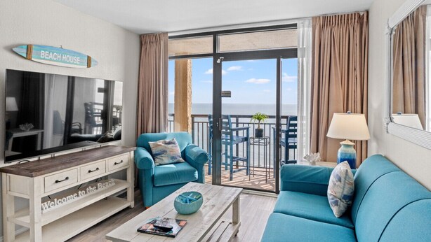 Una sala de estar moderna con una televisión, un sofá, una mesa de centro y un letrero que dice "Welcome to the Beach House".