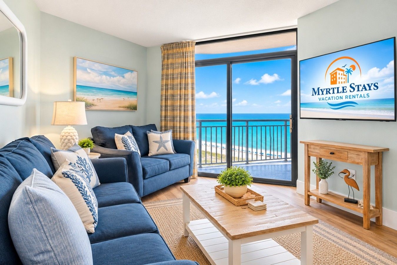 A modern living room with a large sofa, a coffee table, and a view of the beach.