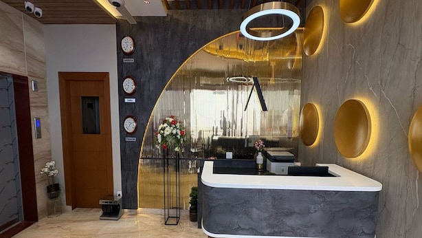 A modern reception area with a marble floor, a reception desk, and a decorative wall with circular lights. - EMBASSY PARK Near US consulate (Chennai)
