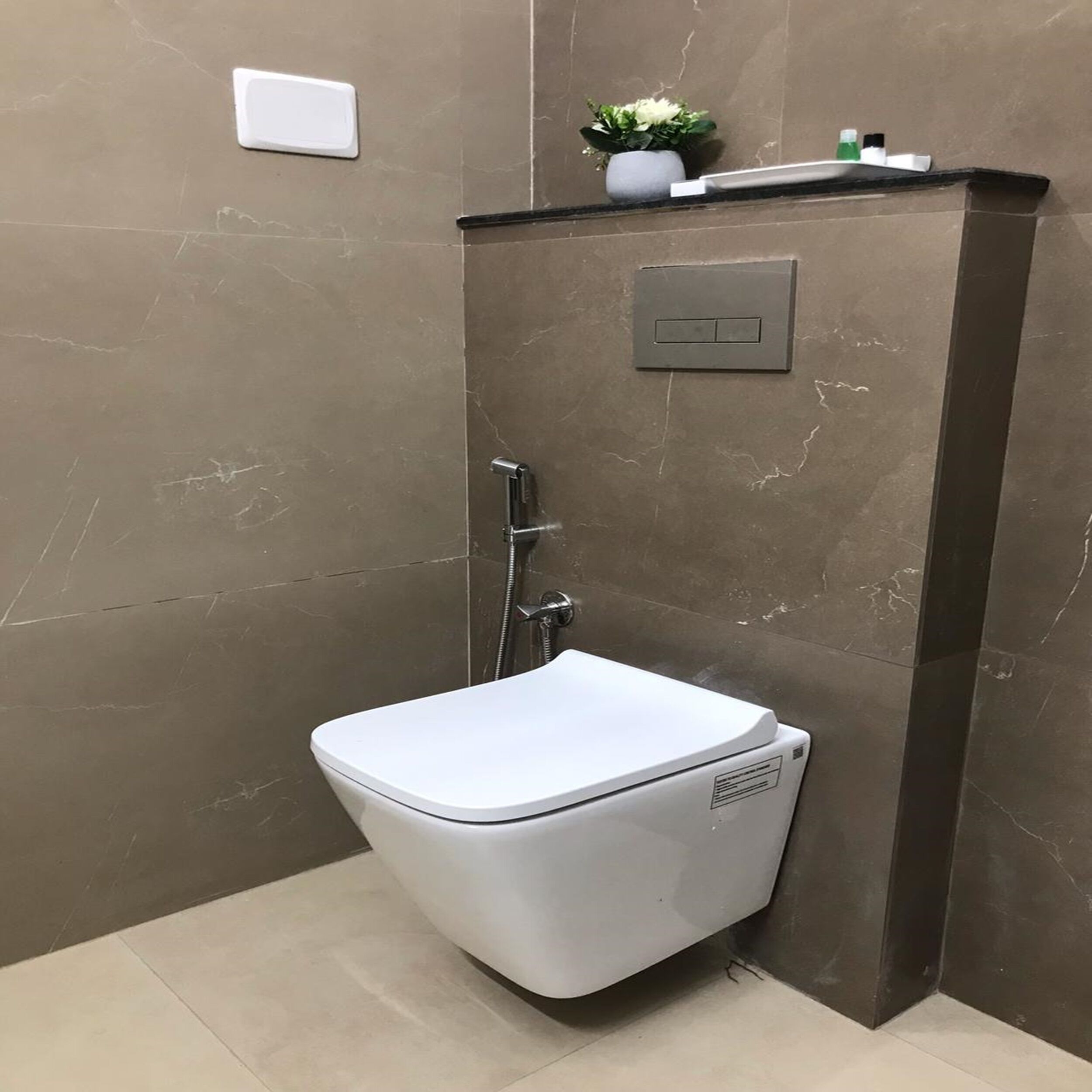 A modern bathroom with a white toilet, a shower, and a control panel on the wall.