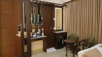 A hotel room with two beds, a desk with a TV, a chair, and a wardrobe.
