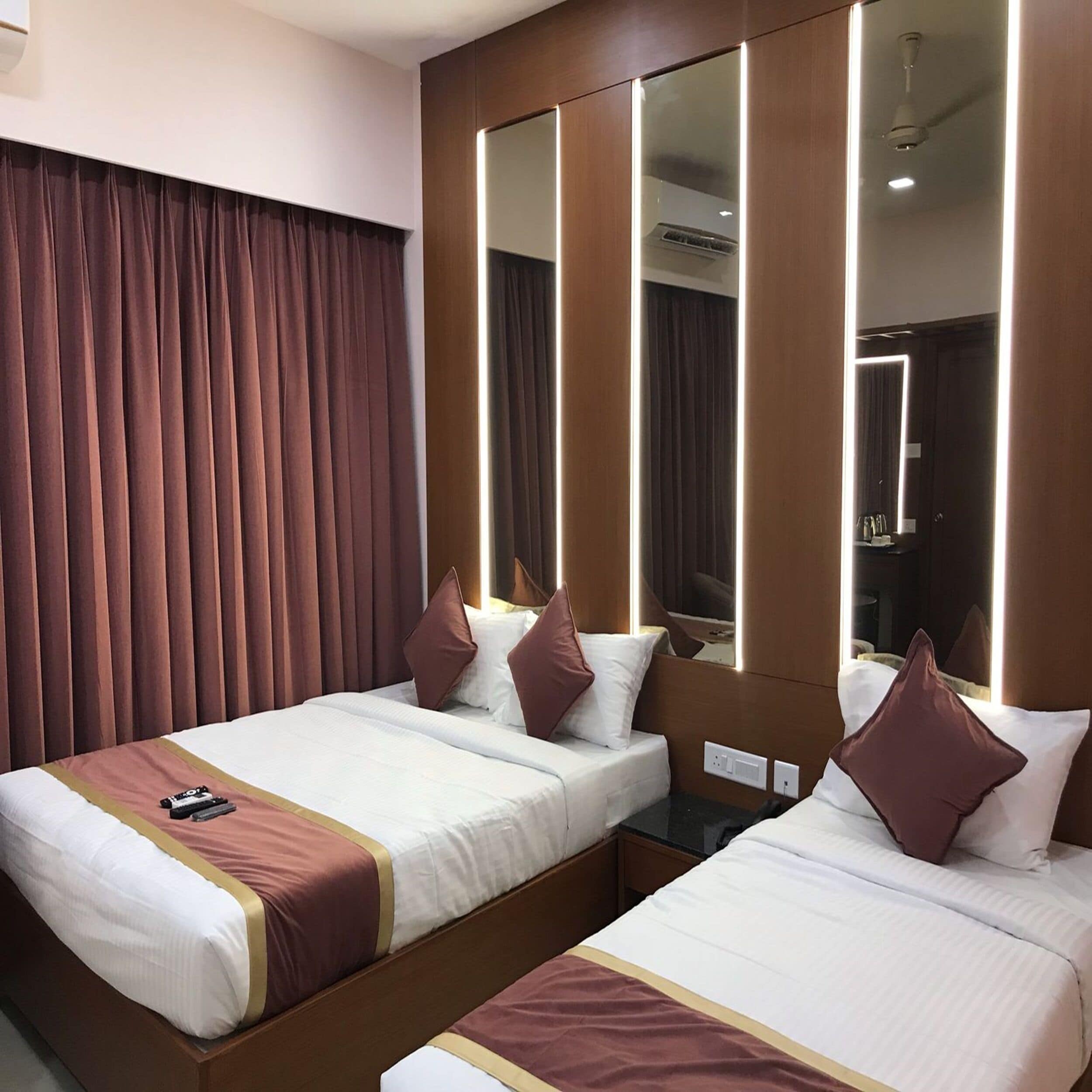 Ein Hotelzimmer mit zwei Betten, einem großen Spiegel und einem Vorhang.