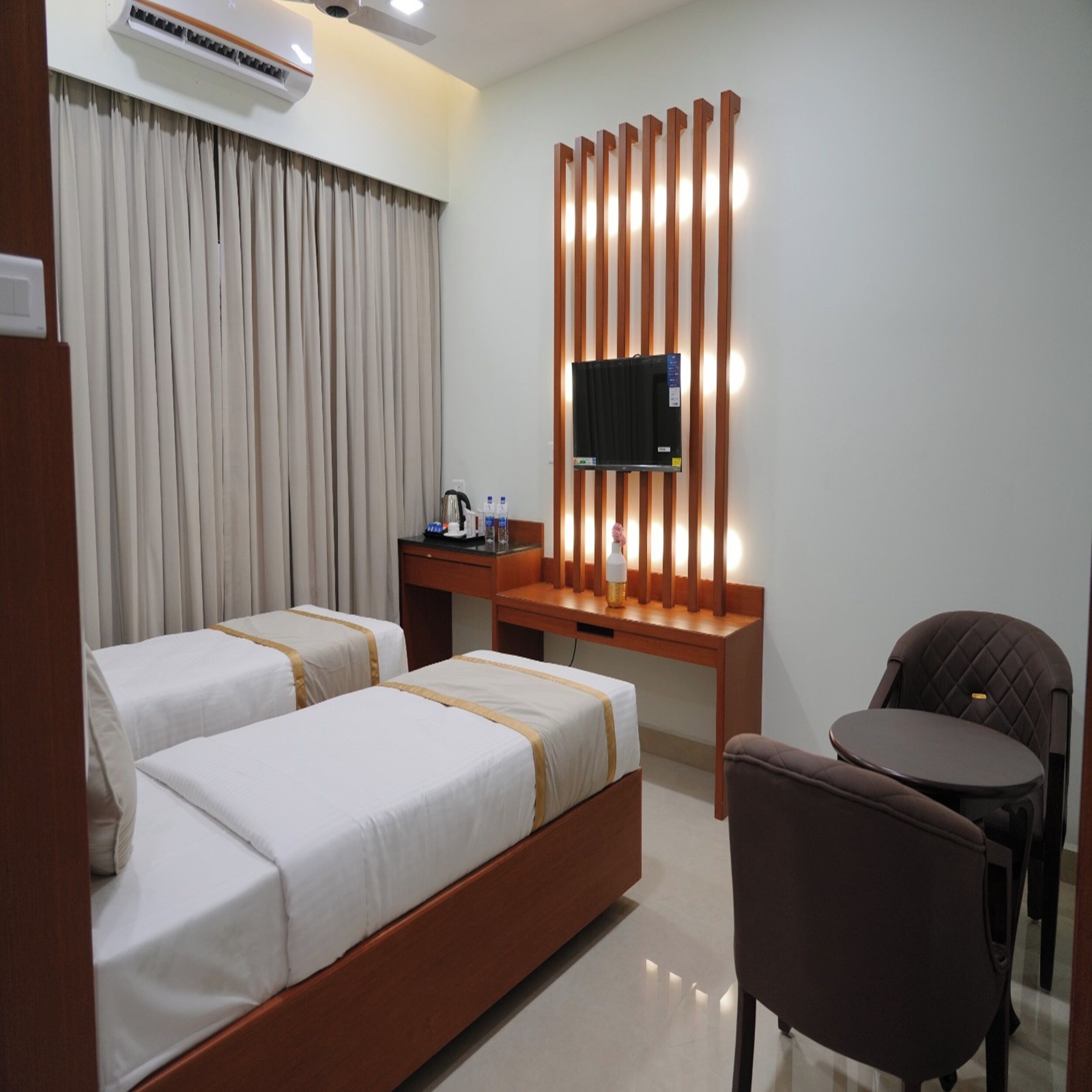 Une chambre d’hôtel avec deux lits, un bureau doté d’un téléviseur à écran plat, une chaise et une petite table.