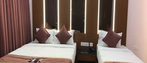 Habitación de hotel con dos camas, un espejo y una mesita de noche con teléfono.
