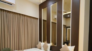 A hotel room with two beds, a large mirror, and a green chair. - EMBASSY PARK Near US consulate (Chennai)