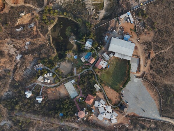 Vista aérea de una propiedad rural con varias construcciones, un extenso campo abierto y un estanque.