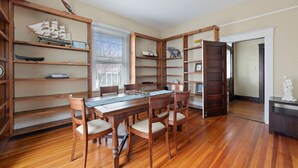 A dining room with a wooden table and chairs, surrounded by wooden bookshelves filled with various items. - Downtown Luray Historic Home: Shenandoah • Caverns (Luray)