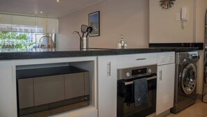 Una cocina moderna con electrodomésticos integrados, una lámpara colgante y vistas al exterior.