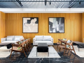 En moderne lobby med to sofaer, et sofabord og træstole.