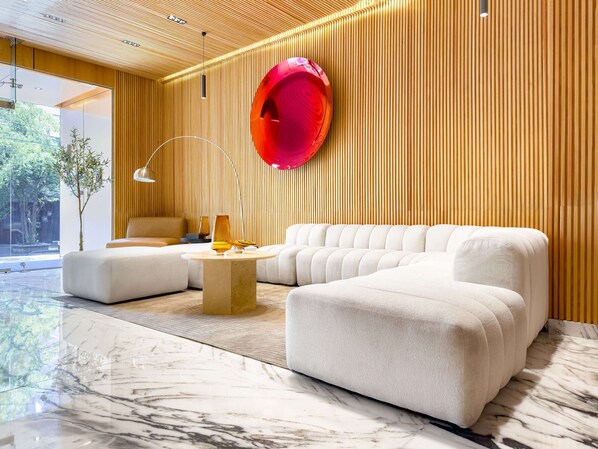 A modern living room with a sectional sofa, a round coffee table, and a red spherical object on the wall.