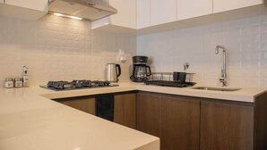 A modern kitchen with a stainless steel range hood, a coffee maker, and a sink.