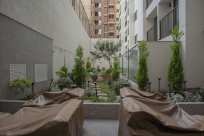 A covered outdoor seating area with tables, surrounded by greenery and a view of a multi-story building. - w* | Stylish 1BR with Balcony in Miraflores (Miraflores)