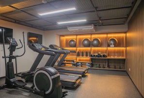 A gym with treadmills, an elliptical, and a wall with exercise equipment and weights. - w* | Stylish 1BR with Balcony in Miraflores (Miraflores)