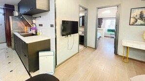 A modern kitchen with a built-in oven, a microwave, and a sink. There is a dining area with a table and chairs. - Tech-X apartment hotel (Shanghai)