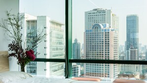 A hotel room with a large window offering a view of tall buildings. - Tech-X apartment hotel (Shanghai)