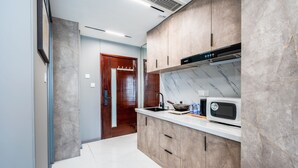 A modern kitchen with a marble backsplash, wooden cabinets, and a built-in microwave. - Tech-X apartment hotel (Shanghai)