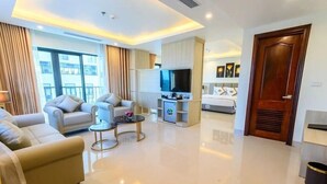 A modern hotel room with a living area featuring a sofa, armchairs, a coffee table, and a TV. - Phuc Anh Hotel Sam Son -BAYLUXURY (Sam Son)
