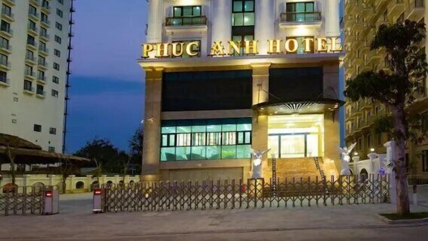 A tall hotel building with multiple balconies and a well-lit entrance. - Phuc Anh Hotel Sam Son -BAYLUXURY (Sam Son)