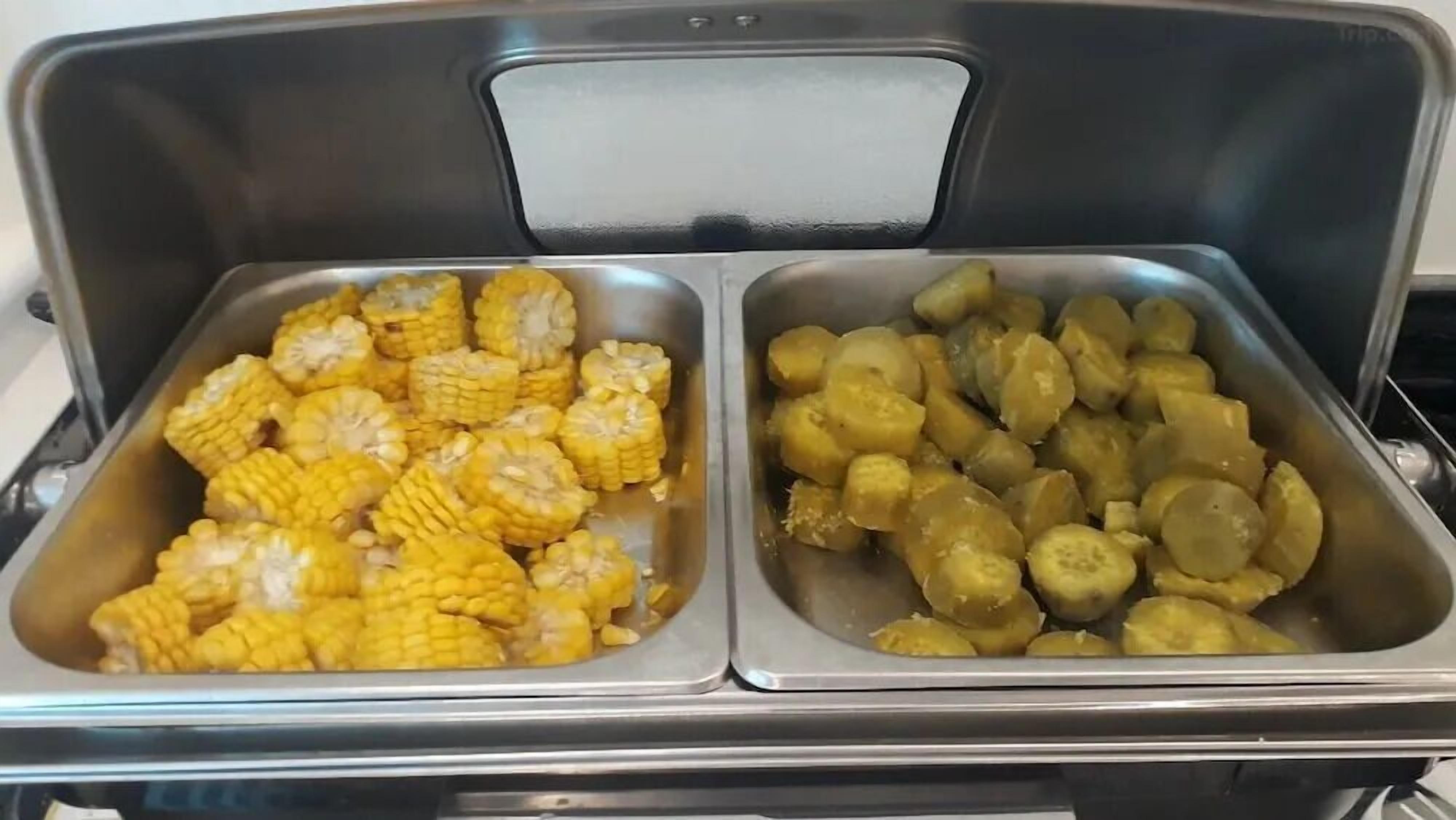 Buffet com duas travessas, uma com espigas de milho e a outra com quiabo fatiado.