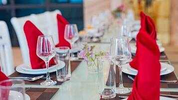 A dining table set with white plates, red napkins, and clear glasses.
