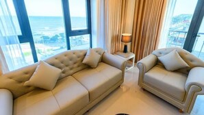 A modern living room with two sofas and a lamp, large windows with a view of the sea, and a curtain. - Phuc Anh Hotel Sam Son -BAYLUXURY (Sam Son)