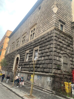 A stone building with a large arched entrance, a series of windows, and a metal fence. - AR.b&b in the heart of Naples (Napoli)