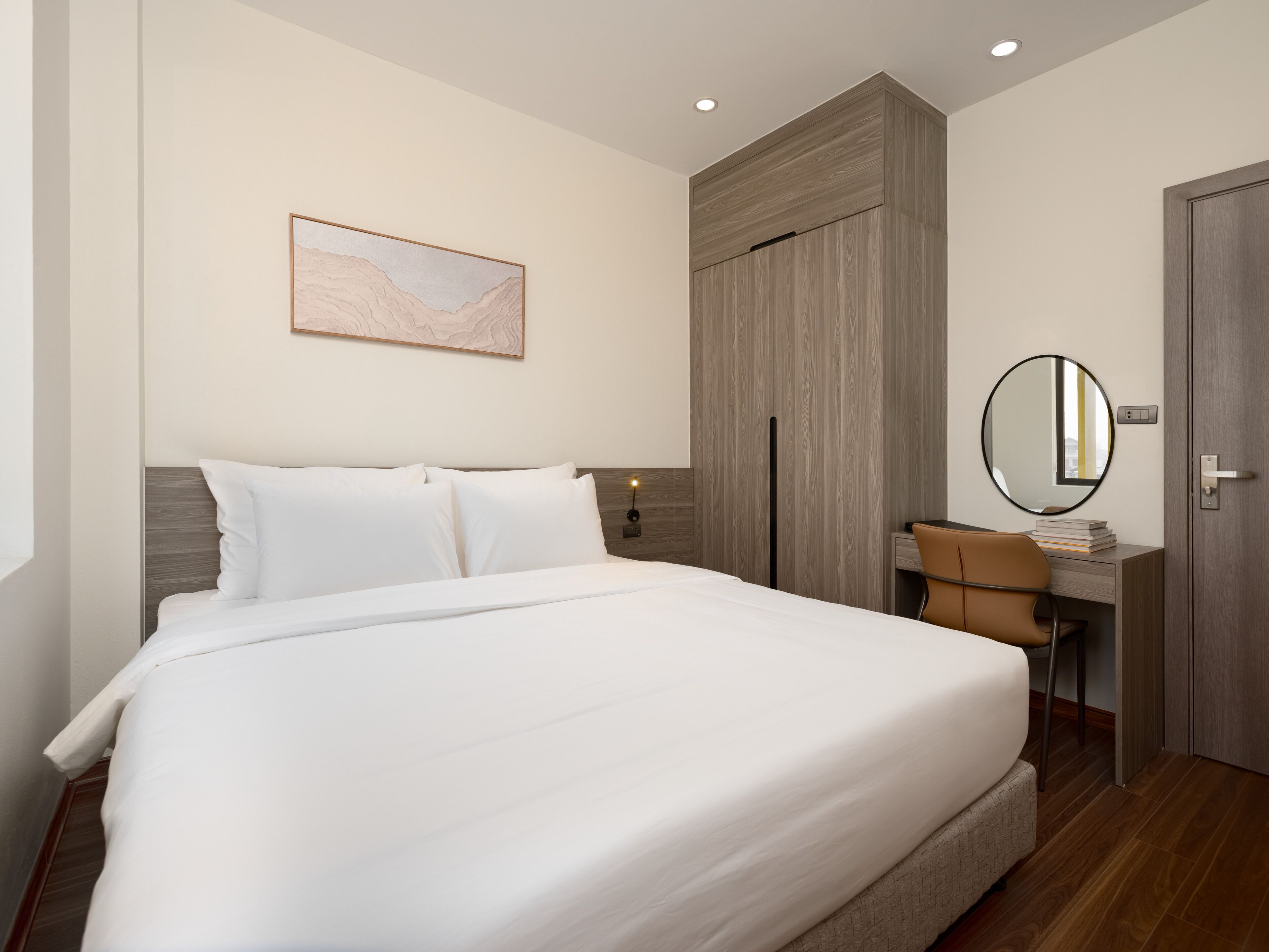 Ein Hotelzimmer mit einem großen Bett, einem Schreibtisch mit Stuhl, einem Spiegel und einem Kleiderschrank.