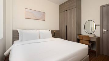 Ein Hotelzimmer mit einem großen Bett, einem Schreibtisch mit Stuhl, einem Spiegel und einem Kleiderschrank.