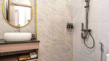 Een moderne badkamer met een marmeren wastafel, een ronde spiegel, een douchekop en een toilet.