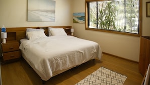 A neatly made bed with a white bedspread, wooden headboard, and two bedside tables with lamps.