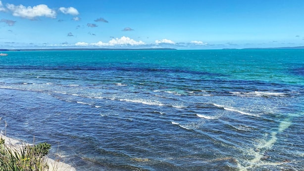 A coastal view with clear turquoise waters and a distant island.