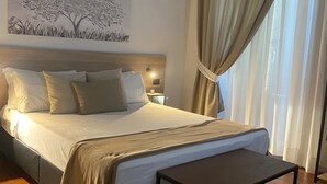 Una cama bien hecha con cabecera, mesita de noche y lámpara de pared.
