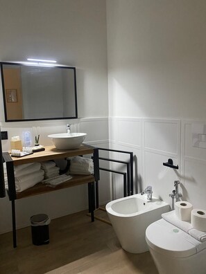 A bathroom with a sink, mirror, towel rack, bidet, toilet, and a trash bin. - AR.B&B in the heart of Naples (Napoli)