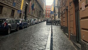 Una estrecha calle adoquinada flanqueada por edificios históricos, algunos con balcones y letreros.