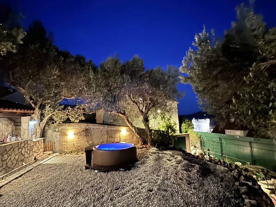 A backyard with a hot tub, stone walls, and a stone pathway.