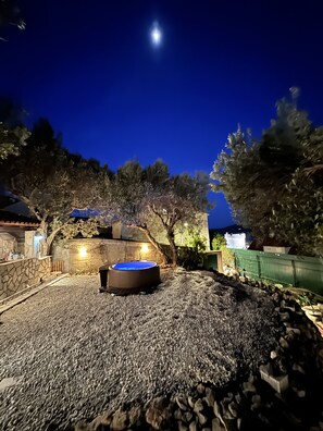 Un patio trasero con jacuzzi, muros de piedra y un camino de piedra.