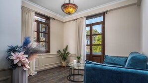 A room with a blue sofa, a glass table with a candle, a decorative plant, and a stained glass ceiling light. - Alegrand Suites (Rhodes)