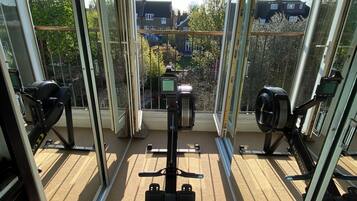 A balcony with exercise equipment and a view of residential buildings.