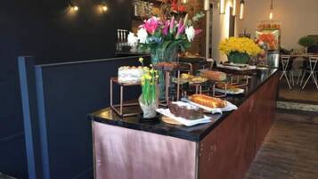 A buffet setup with various food items and a vase of flowers.