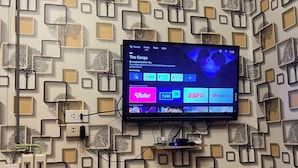 Ein Zimmer mit Wandgestaltung, einem an der Wand montierten Flachbildfernseher, einem kleinen Lautsprecher und einer Klimaanlage.