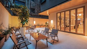 An outdoor patio with seating and plants, a large potted plant, and a view of the interior through glass doors. - Cheens Hotel (Chengdu)