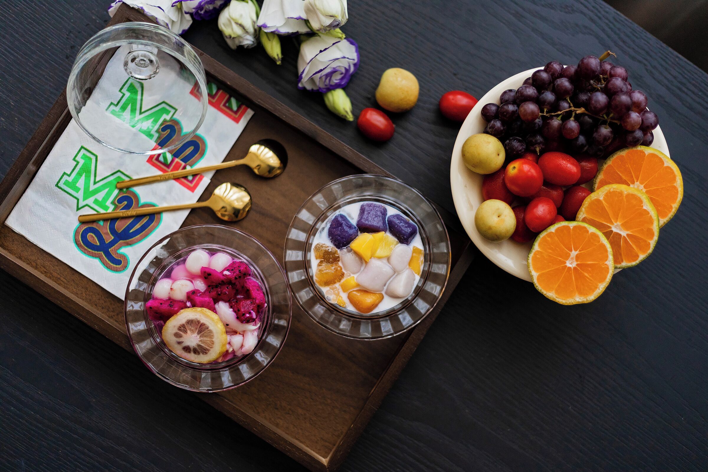 A tray with a variety of fruits and desserts, including grapes, oranges, and colorful ice cubes.