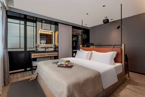 A modern hotel room with a large bed, a bedside table, a mirror, a dresser, and a small plant. - Cheens Hotel (Chengdu)
